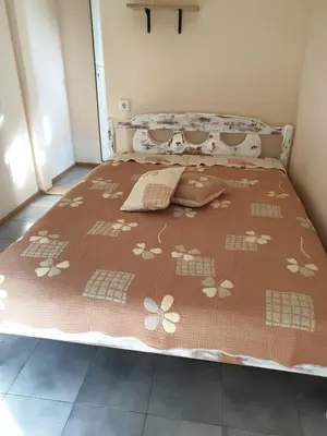 a bed with a brown bedspread with flowers on it at Villa Izgrev 24а in Chernomorets