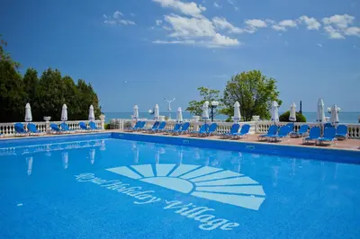 a large swimming pool with blue chairs and the ocean at Villas Elenite in Elenite