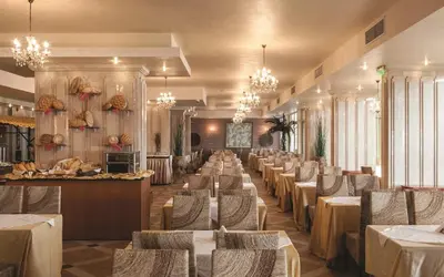 a dining room with tables and chairs and chandeliers at Villas Elenite in Elenite