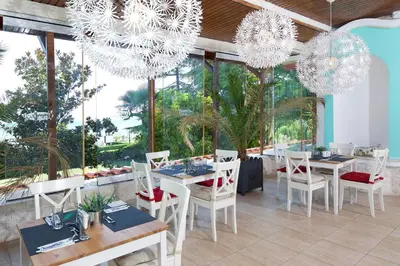a dining room with tables and chairs and chandeliers at Villas Elenite in Elenite
