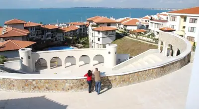 two people standing on a wall looking at the houses at Arena 65m2 - 1 bedroom, 1st line to the beach in Sveti Vlas
