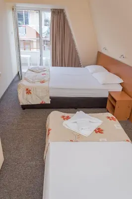 a hotel room with two beds and a window at Hotel Eva in Ravda
