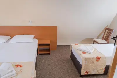 a hotel room with two beds and a chair at Hotel Eva in Ravda