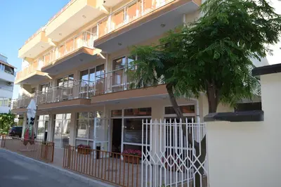 a building with a white fence and a tree at Hotel Eva in Ravda