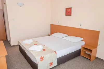 a small bedroom with a bed with white sheets at Hotel Eva in Ravda