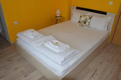 a bed with white sheets and towels on it at Villa Valentines in Kiten