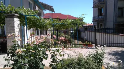 a black fence with flowers in front of a building at Песента на морето in Obzor