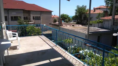 a balcony with a blue fence next to a building at Песента на морето in Obzor