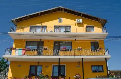 a yellow apartment building with balconies and windows at Morski Rai Rooms in Byala