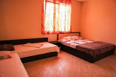 two beds in a room with a window and a couch at Villa Yanevi in Lozenets