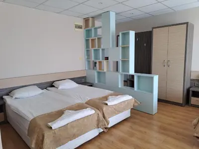 a bedroom with a large bed and a book shelf at Hotel City in Burgas City