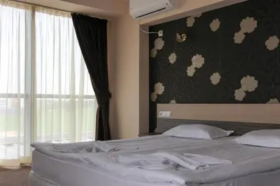 a bedroom with a large bed with a window at Hotel City in Burgas City