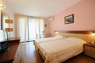 a bedroom with two beds and a flat screen tv at Guest House Daris in Sozopol