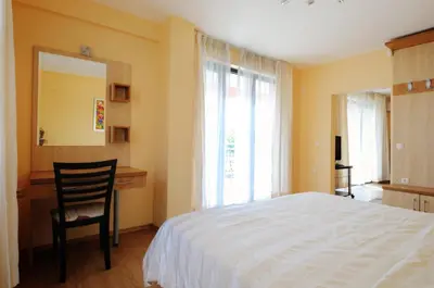 a bedroom with a bed and a chair and a mirror at Guest House Daris in Sozopol