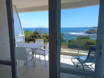 a balcony with a table and chairs and a view of the ocean at Aparthotel Romance in Kiten