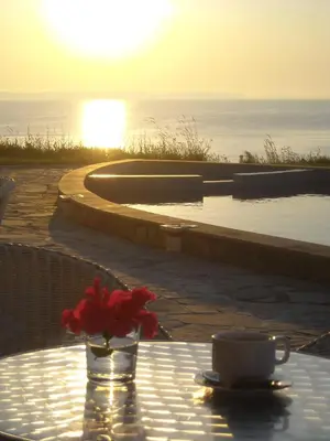 a table with a cup of coffee and a vase with a flower at Aparthotel Romance in Kiten
