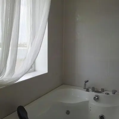 a white bathroom with a tub and a window at Aparthotel Romance in Kiten