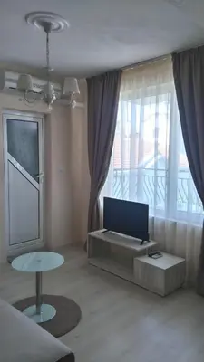 a living room with a television and a table in front of a window at Guest House Adriya in Primorsko