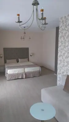 a bedroom with a bed and a couch and a chandelier at Guest House Adriya in Primorsko