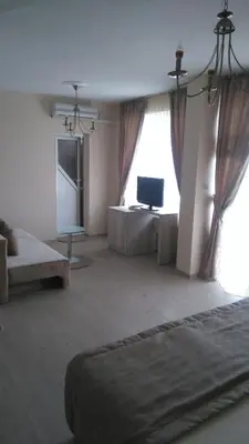 a large room with a bed and a television at Guest House Adriya in Primorsko