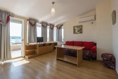 a living room with a red couch and a desk at Семеен хотел Бриз in Sozopol