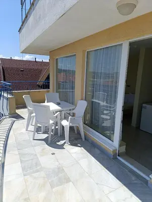 a patio with a table and chairs on a balcony at Семеен хотел Бриз in Sozopol
