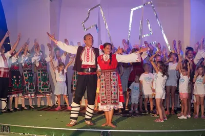 a man and woman standing on a stage with a group of children at Hotel Wela - Premium All Inclusive in Sunny Beach