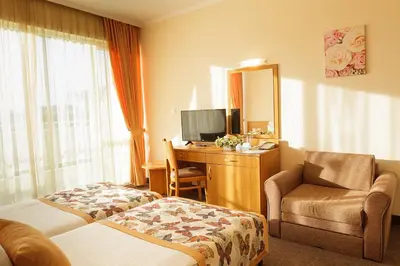 a hotel room with a bed and a desk with a mirror at Hotel Wela - Premium All Inclusive in Sunny Beach