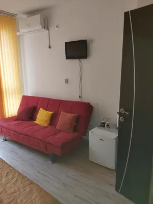 a red couch with yellow pillows in a living room at Apartament Janet in Pomorie