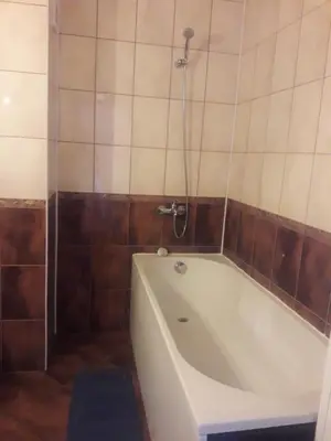 a bath tub in a bathroom with a tiled wall at Apartament Janet in Pomorie