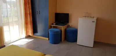a room with a tv and two stools and a refrigerator at Hotel Laguna - Guest House in Primorsko