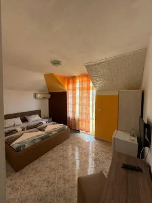 a bedroom with two beds and a table in a room at Hotel Laguna - Guest House in Primorsko