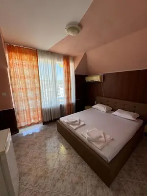 a bedroom with a bed and a large window at Hotel Laguna - Guest House in Primorsko