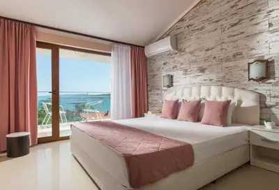 a bedroom with a large bed and a large window at Семеен хотел Golden Place in Sozopol