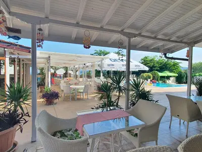 a patio with a table and chairs and a pool at Семеен хотел Golden Place in Sozopol
