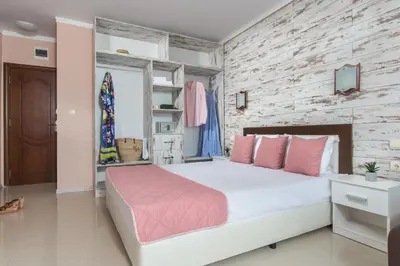 a bedroom with a large white bed with pink pillows at Семеен хотел Golden Place in Sozopol