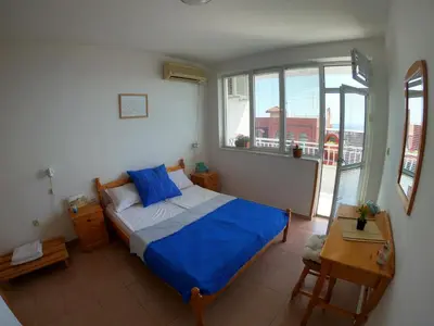 a bedroom with a bed with blue sheets and a window at Apartment in St. Vlas with terrace in Sveti Vlas
