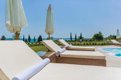 a group of lounge chairs with umbrellas and a pool at Apartments in Complex Sunny Island Deluxe in Chernomorets