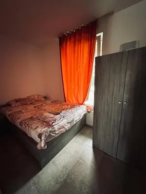 a bedroom with a bed with an orange curtain at Stella Udacha Apartments & Studios in Sunny Beach