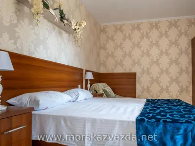 a bedroom with a large bed with a wooden headboard at Hotel Morska Zvezda in Sozopol