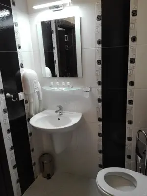 a bathroom with a sink and a toilet and a mirror at Апартамент Дарко in Pomorie