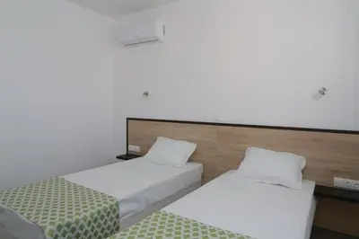 two beds in a hotel room with white walls at St. Stefan Villas & Hotel in Sozopol