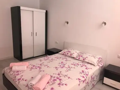 a bedroom with a bed with pink sheets and a mirror at Apartamenti Eli in Pomorie