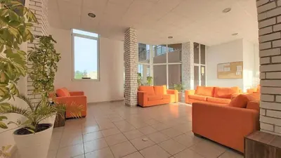 a living room with orange furniture and windows at Sanny view South- Студия Мир авангарда in Sunny Beach