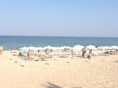 a group of people on a beach with umbrellas at Family Hotel Orios in Primorsko