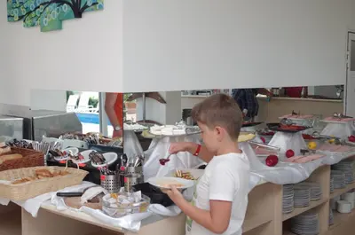 a boy standing at a buffet with a plate of food at Family Hotel Orios in Primorsko