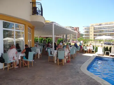 a group of people sitting at a restaurant next to a pool at Family Hotel Orios in Primorsko