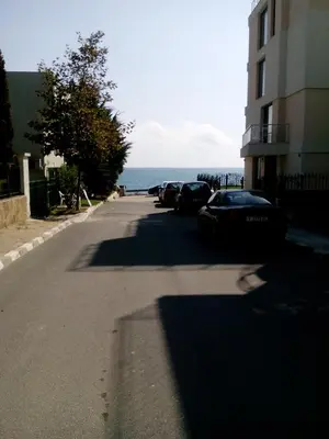 a street with cars parked next to a building and the ocean at Villa Gracia in Ravda