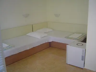 two twin beds in a small room with a refrigerator at Guest House Dimovi in Sozopol