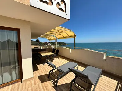 a balcony with chairs and tables and the ocean at Hotel Capri in Nesebar